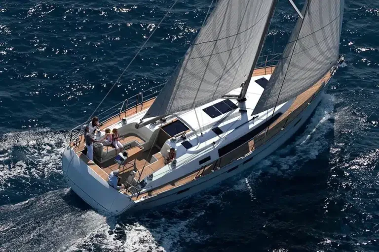 Luftaufnahme eines luxuriösen Katamarans, der auf klarem, blauem Wasser kreuzt. An Deck sind vier Personen zu sehen, die die Fahrt genießen.