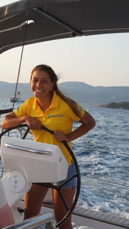 Skipperin Xenia steuert ein Segelboot im Sailwithus-T-Shirt