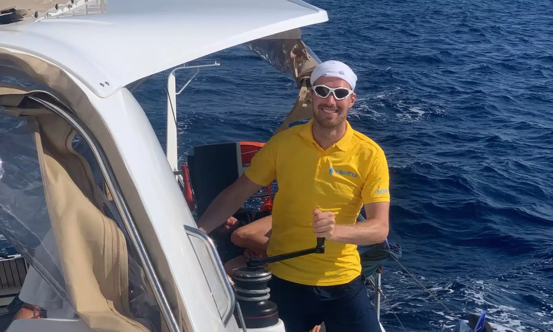 Skipper Benedikt steuert ein Segelboot im Sailwithus-T-Shirt