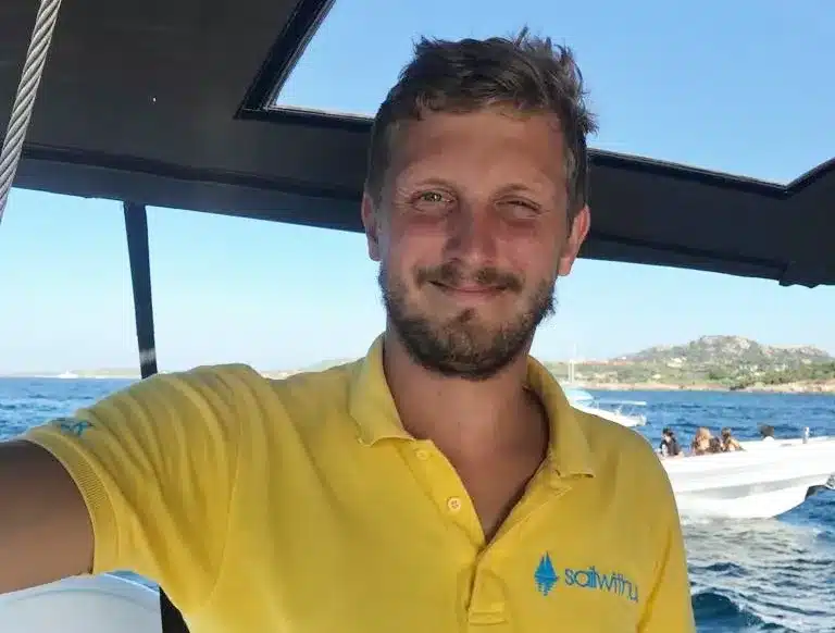 Skipper Benjamin steuert ein Segelboot im Sailwithus-T-Shirt