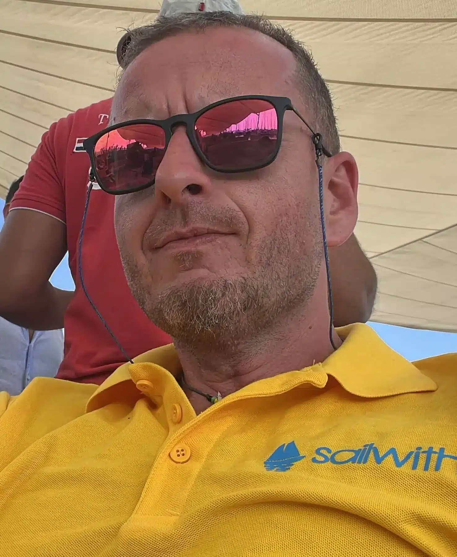 Skipper Jürgen steuert ein Segelboot im Sailwithus-T-Shirt