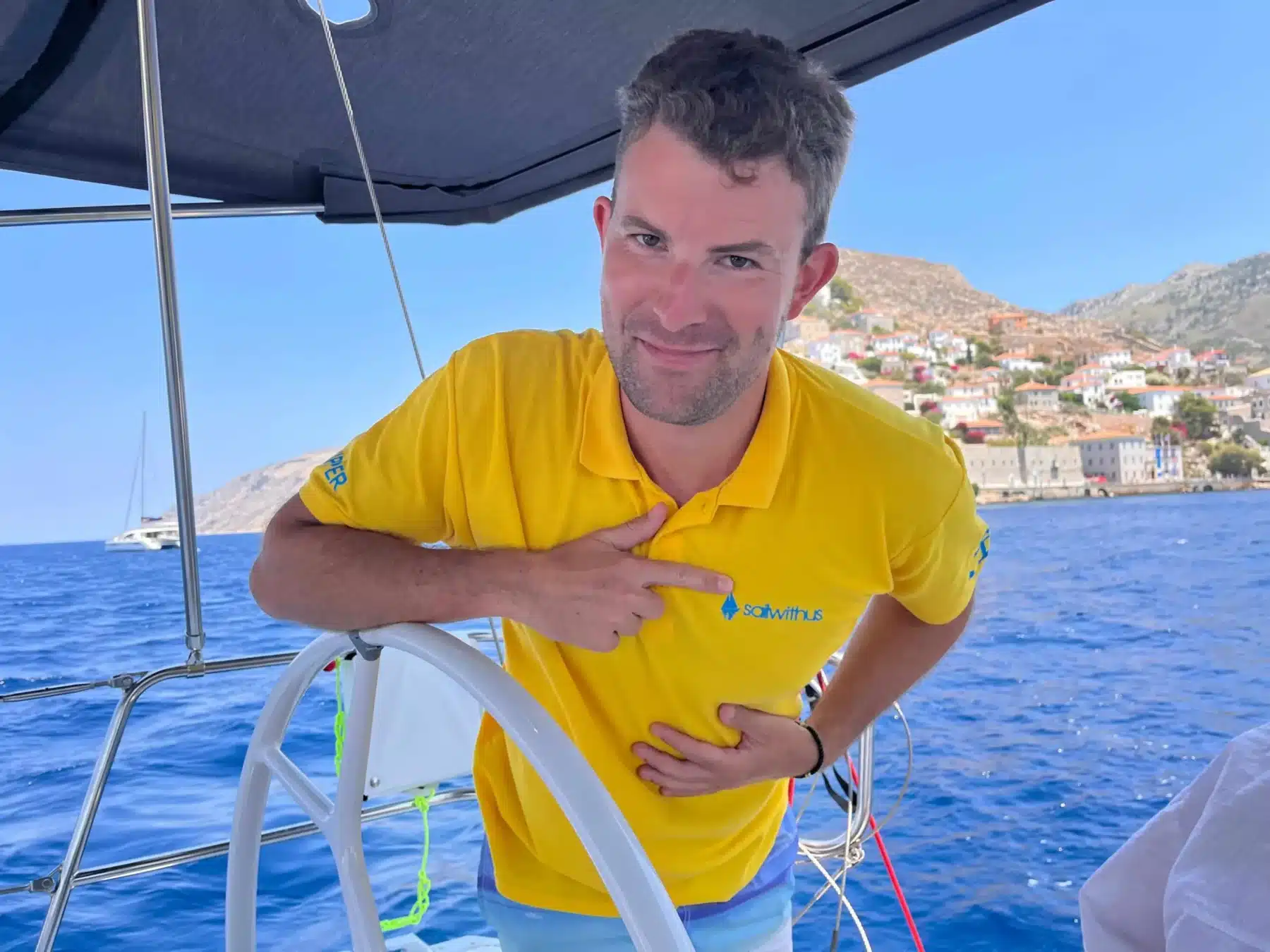 Skipper Moritz steuert ein Segelboot im Sailwithus-T-Shirt