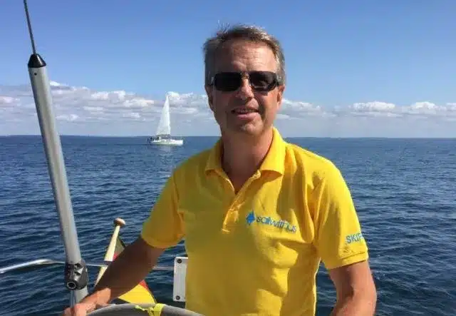 Skipper Rainer steuert ein Segelboot im Sailwithus-T-Shirt