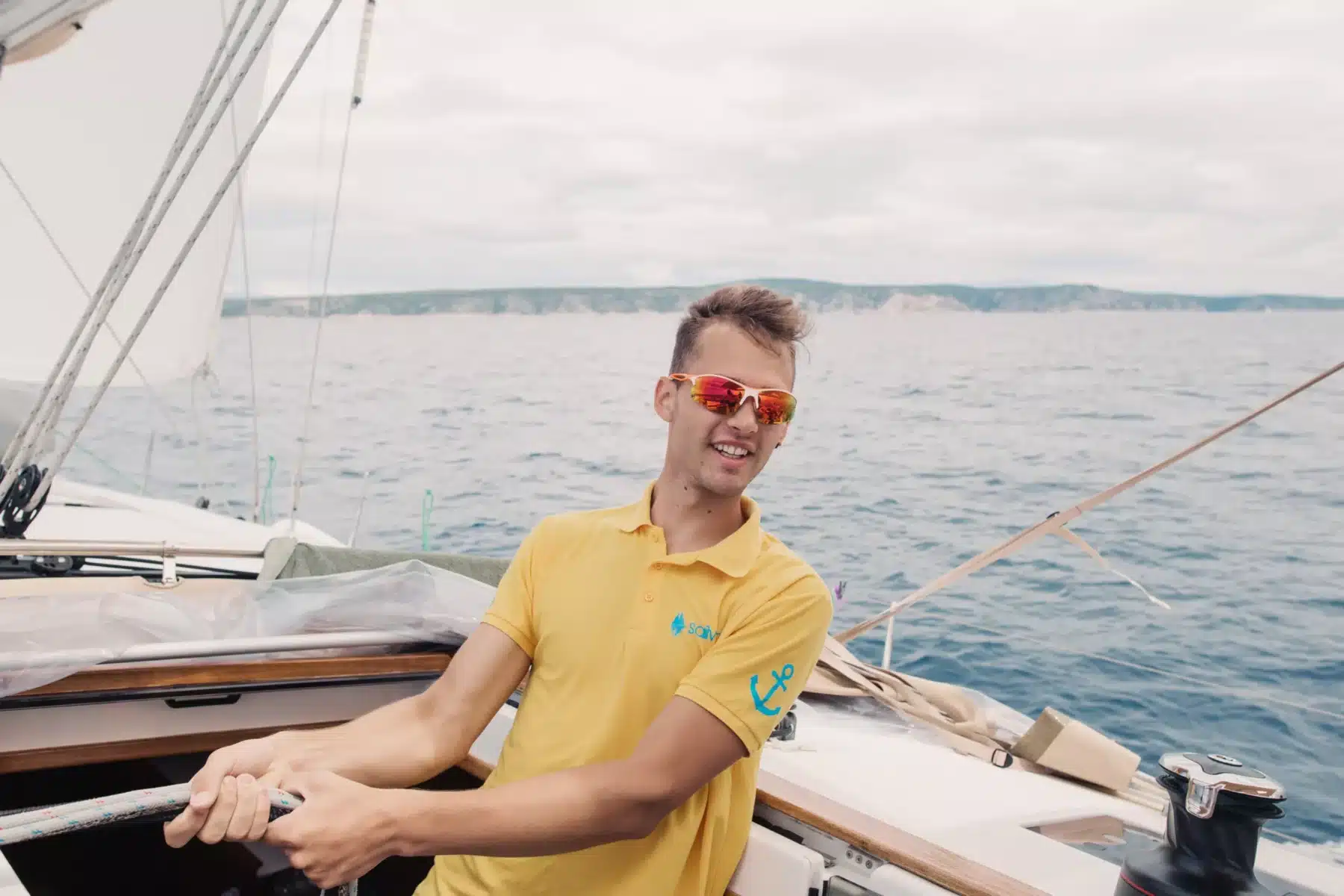 Skipper Simon steuert ein Segelboot im Sailwithus-T-Shirt