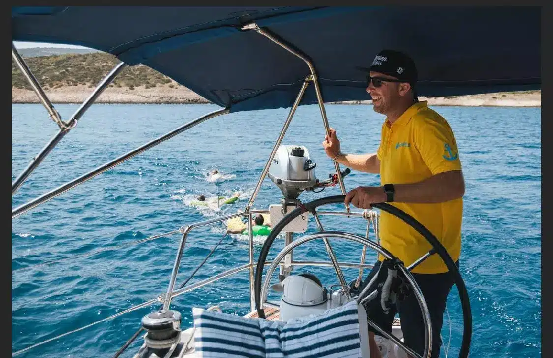 Skipper Dominic steuert ein Segelboot im Sailwithus-T-Shirt