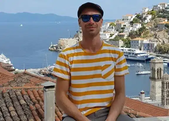 Skipper Dirk steuert ein Segelboot im Sailwithus-T-Shirt