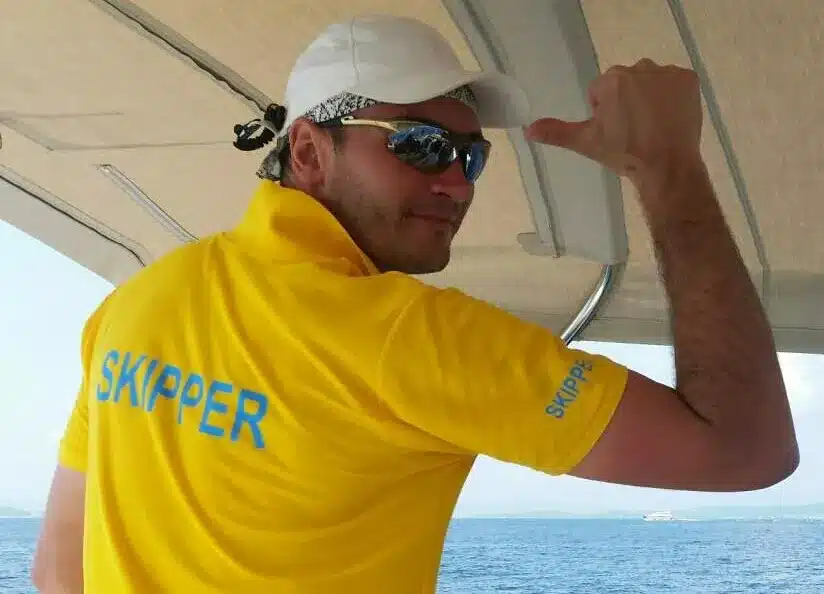 Skipper Konstantin steuert ein Segelboot im Sailwithus-T-Shirt