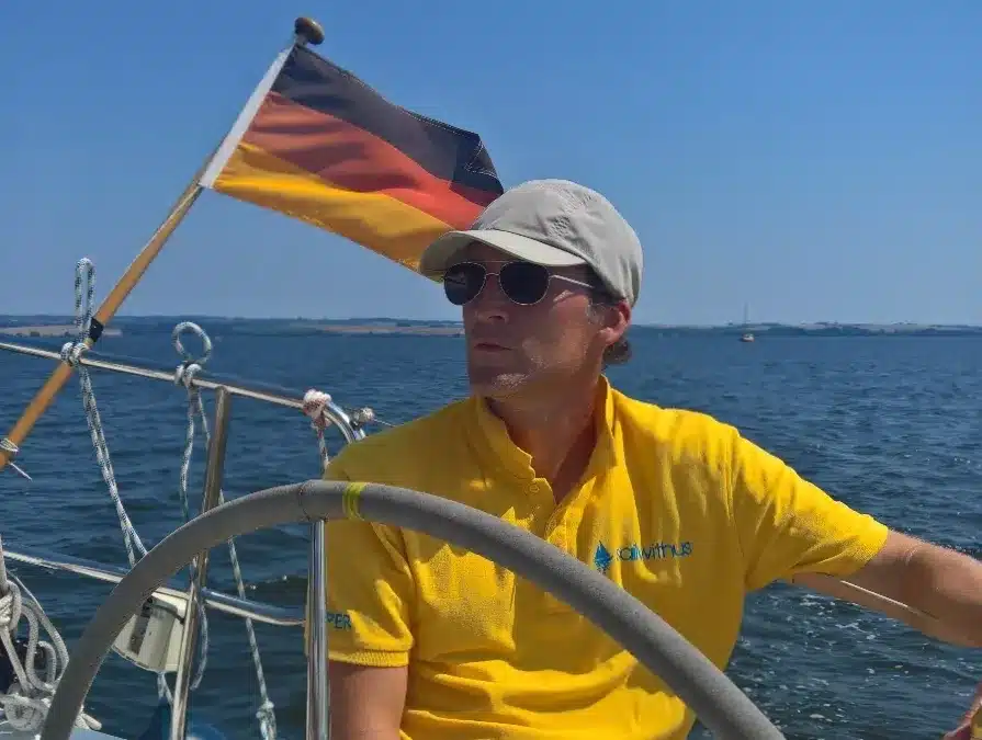 Skipper Gerald steuert ein Segelboot im Sailwithus-T-Shirt