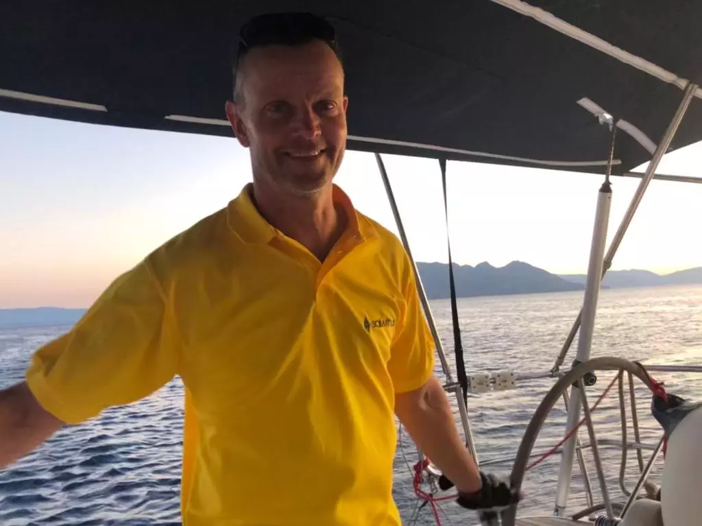 Skipper Andreas steuert ein Segelboot im Sailwithus-T-Shirt