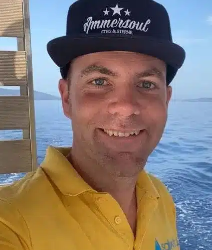 Skipper Simon steuert ein Segelboot im Sailwithus-T-Shirt