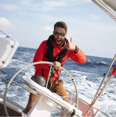 Skipper Max steuert ein Segelboot im Sailwithus-T-Shirt