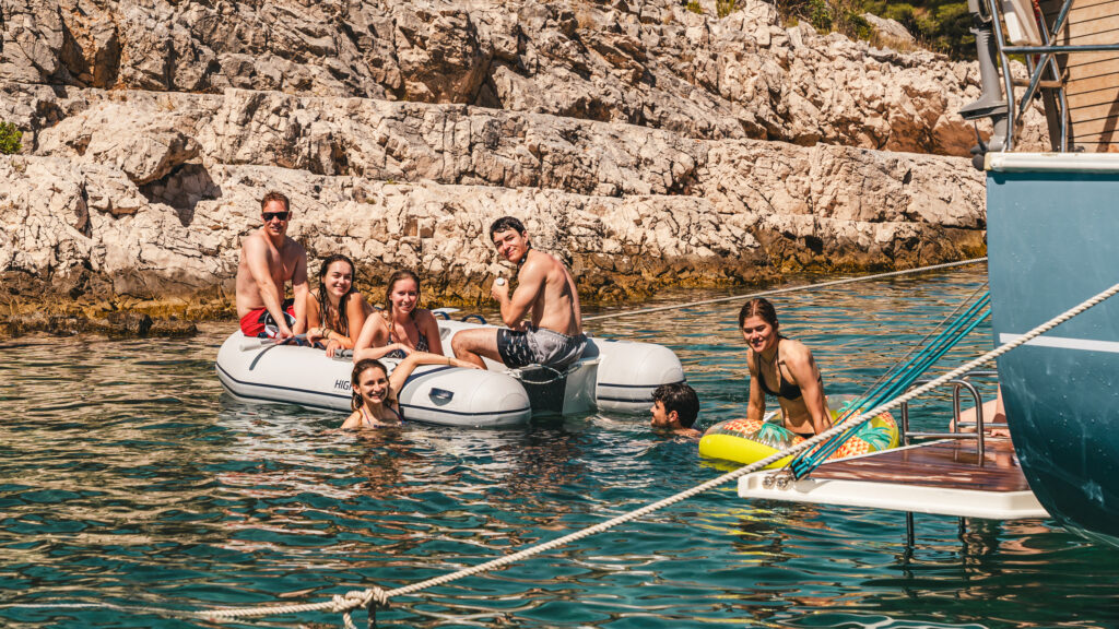 Gruppe auf dem Wasser während ihres Segeltörns. Jungs und Mädchen haben spaß und sich aktiv. Die Aktivitäten und das Entertainment auf dem Wasser bringt alle ein Lächeln. 