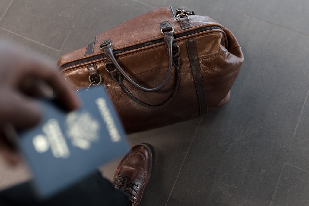 Brown leather bag with passport in an airport setting, ideal for travel and fashion themes. Segelausrüstung